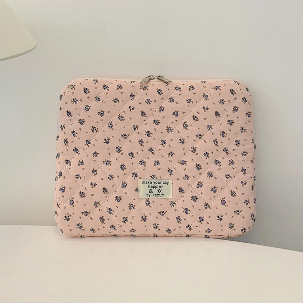 Funda acolchada rosa para portátil con estampado floral y una etiqueta pequeña, mostrada sobre una superficie blanca.
