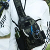 A person holds a camouflage tactical fishing gear storage chest bag against a white long-sleeved shirt.