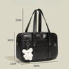 Black waterproof PU leather student messenger bag with a white fluffy charm shown from the side.