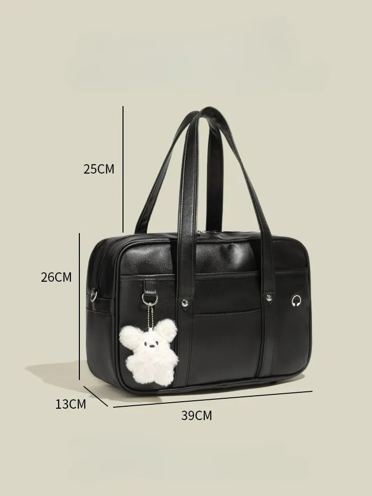 Black waterproof PU leather student messenger bag with a white fluffy charm shown from the side.