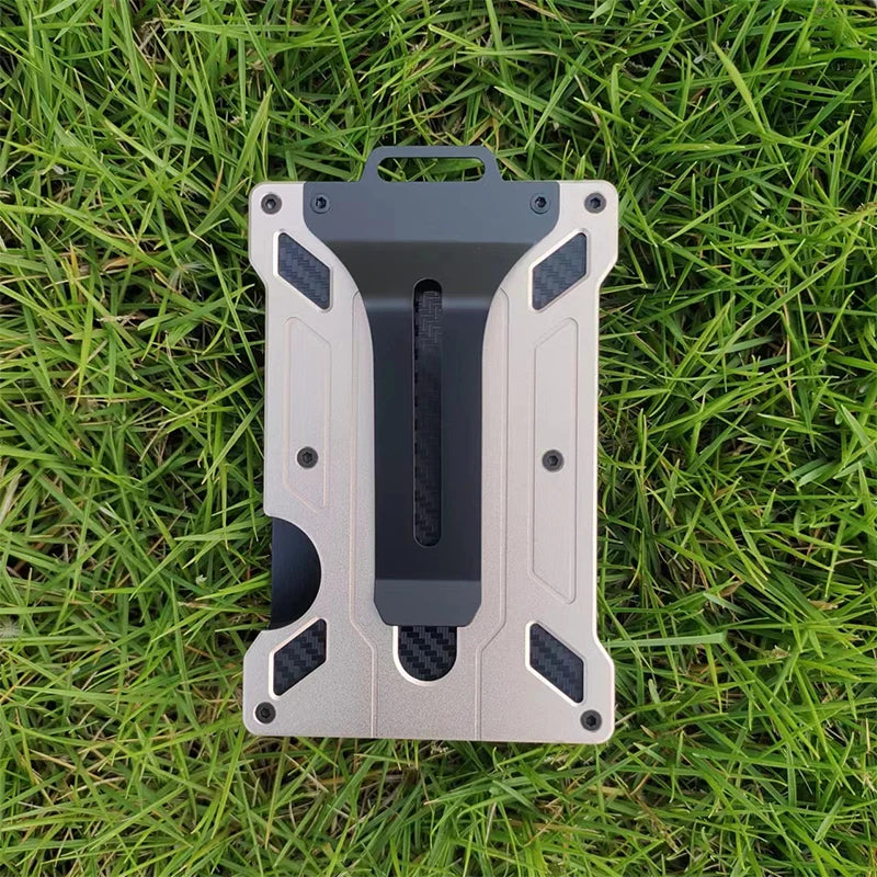 A slim aluminum metal ID card wallet lying on green grass.