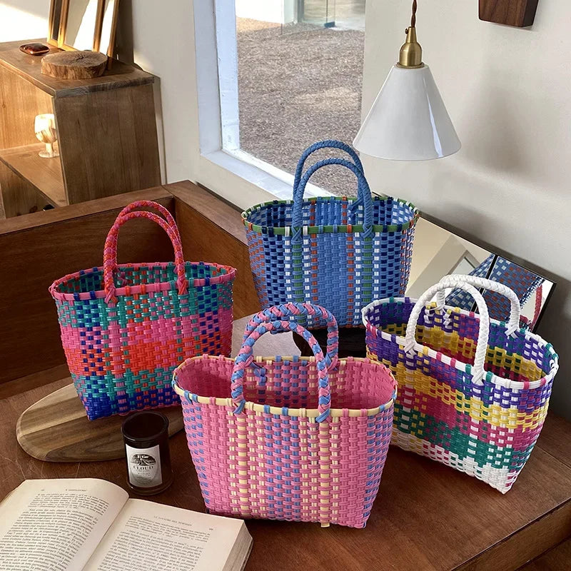 A collection of hand woven PVC vegetable basket tote bags in various colors including pink, purple, green, and yellow.