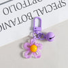 A purple resin flower keychain with a yellow center attached to a silver keyring.