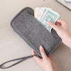 Una mano abre una cartera de pasaporte con bloqueo RFID gris para revelar efectivo y documentos.