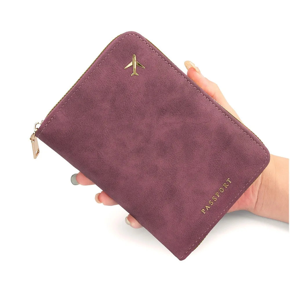 A deep purple passport wallet with a gold airplane emblem is held by a hand.