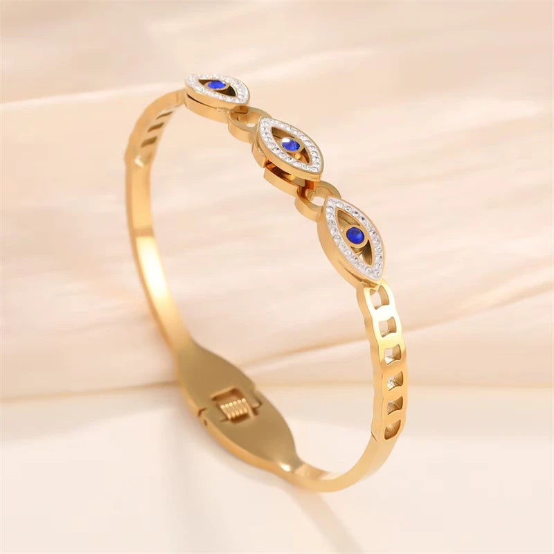 Gold cuff bracelet featuring evil eye crystal designs and blue stones