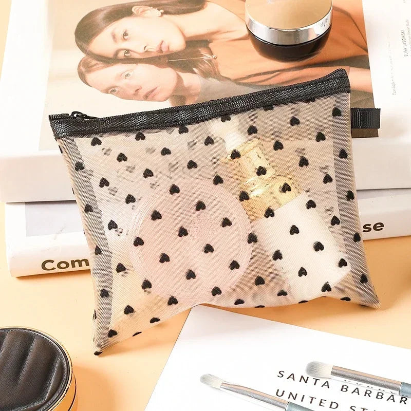 A clear mesh cosmetic storage pouch with black mesh and a gold-colored cosmetic product inside, resting on white paper.