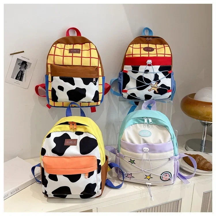 A collection of women's fashion backpacks featuring cow print patterns in black and white, with accents of yellow, orange, an