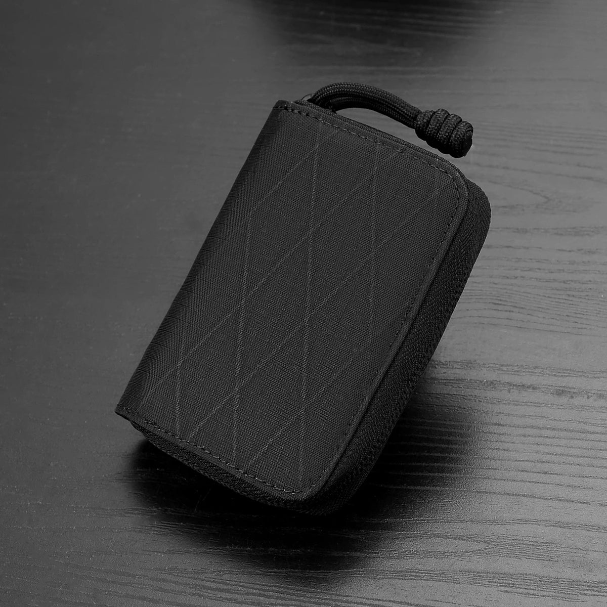 A black RFID zipper wallet is shown lying on a dark wooden surface.