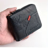A black slim PU leather wallet with a zipper closure is held in a hand.