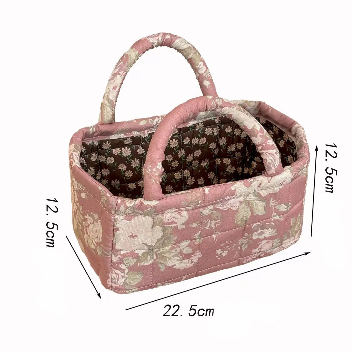 A pink quilted fabric storage basket with a handle and a floral pattern.