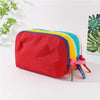 A lightweight travel makeup bag with a red main compartment and colorful accents, resting on a white surface.