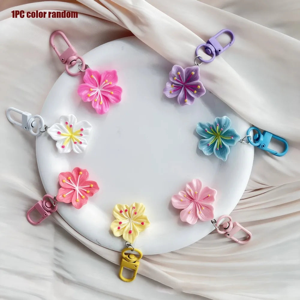 A collection of 12 colorful resin flower keychains in various shades of pink, purple, and blue arranged on a white plate.