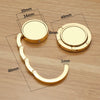 A gold-colored folding alloy handbag hanger hook with various dimensions shown on a wooden surface.