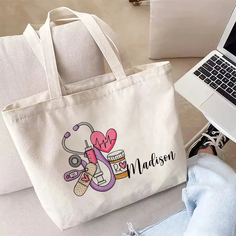 A white canvas tote bag featuring a pink heart and medical symbols, resting on a light surface.