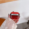 A hand holds a red luminous sand effect earphone case for AirPods against a white background.