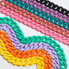 A close-up of multiple strands of colorful matte acrylic choker necklaces arranged diagonally.