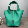 A teal genuine leather bucket bag with a green interior and silver hardware.