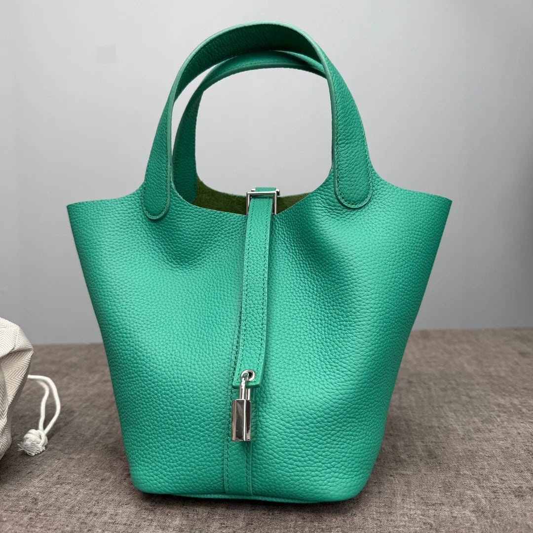 A teal genuine leather bucket bag with a green interior and silver hardware.