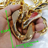 A hand holds a chunky gold acrylic Cuban link necklace, showing its size with a ruler.