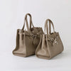 A tan genuine leather women's shoulder tote bag with a flap closure and chain detail.
