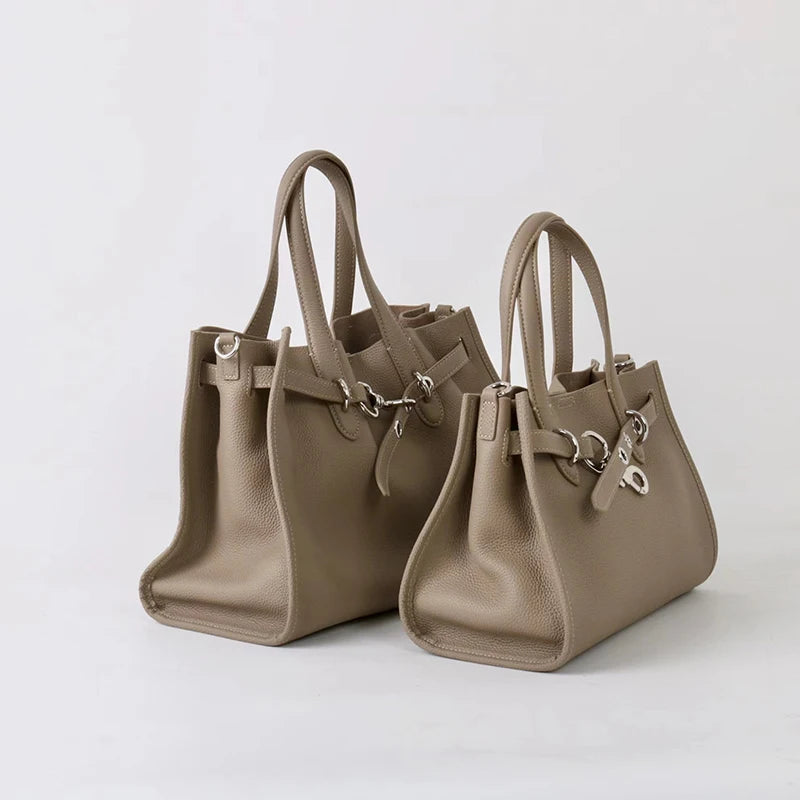 A tan genuine leather women's shoulder tote bag with a flap closure and chain detail.