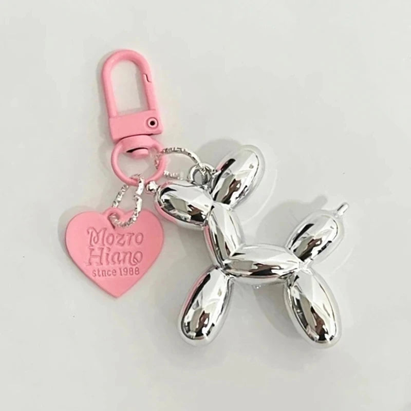 A silver balloon dog keychain charm attached to a pink heart-shaped tag.