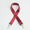 A maroon adjustable nylon shoulder strap in an 'X' shape with metal clasps.