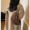 A person wearing a beige trench coat carries a leopard print crossbody bag.