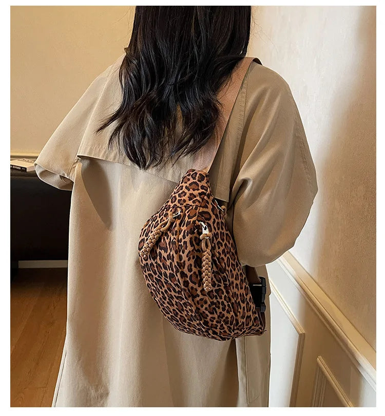 A person wearing a beige trench coat carries a leopard print crossbody bag.