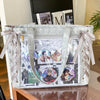 A silver transparent shoulder tote bag with a light pink ribbon, featuring various photo inserts.