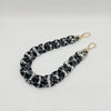 A close-up of a black and white marbled acrylic chain bracelet with gold-toned clasps.