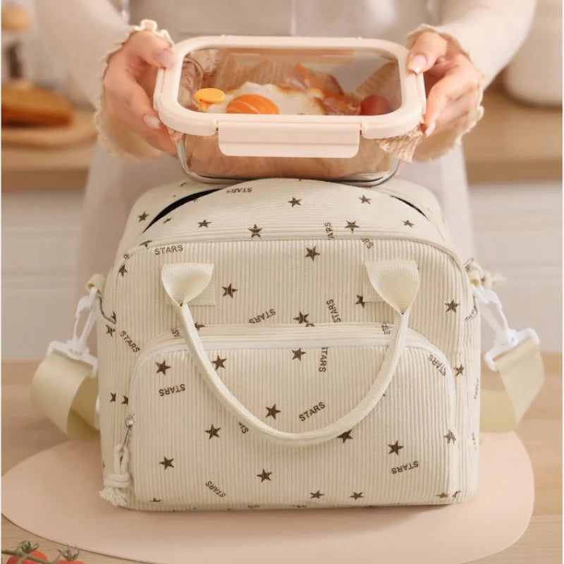 A person holds an orange-colored insulated lunch bag and a clear food container.