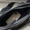 A black soft PU leather shoulder tote bag with a zippered interior showing an Apple phone.