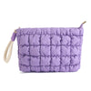 A purple quilted puffer makeup bag with a light-colored strap.