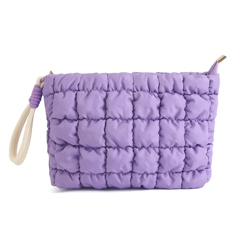 A purple quilted puffer makeup bag with a light-colored strap.