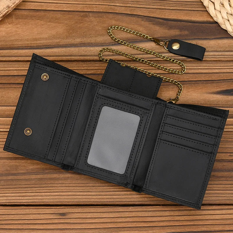 A black men's genuine leather trifold wallet with a detachable gold-toned chain resting on a wooden surface.