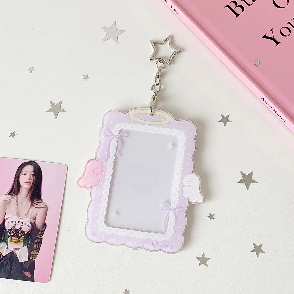 A clear display case shaped like a frame with pink borders and angel wings, attached to a silver charm.