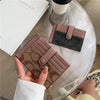Une main tient un porte-cartes en cuir PU marron et fin avec une touche gris foncé sur une surface de verre transparent.