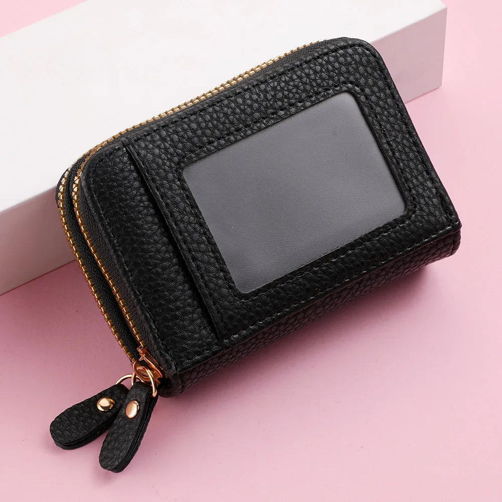 Black floral letter print mini wallet with a double zipper lying on a pink surface.