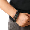 A close-up of a man's wrist wearing a black leather bracelet with tiger eye beads.