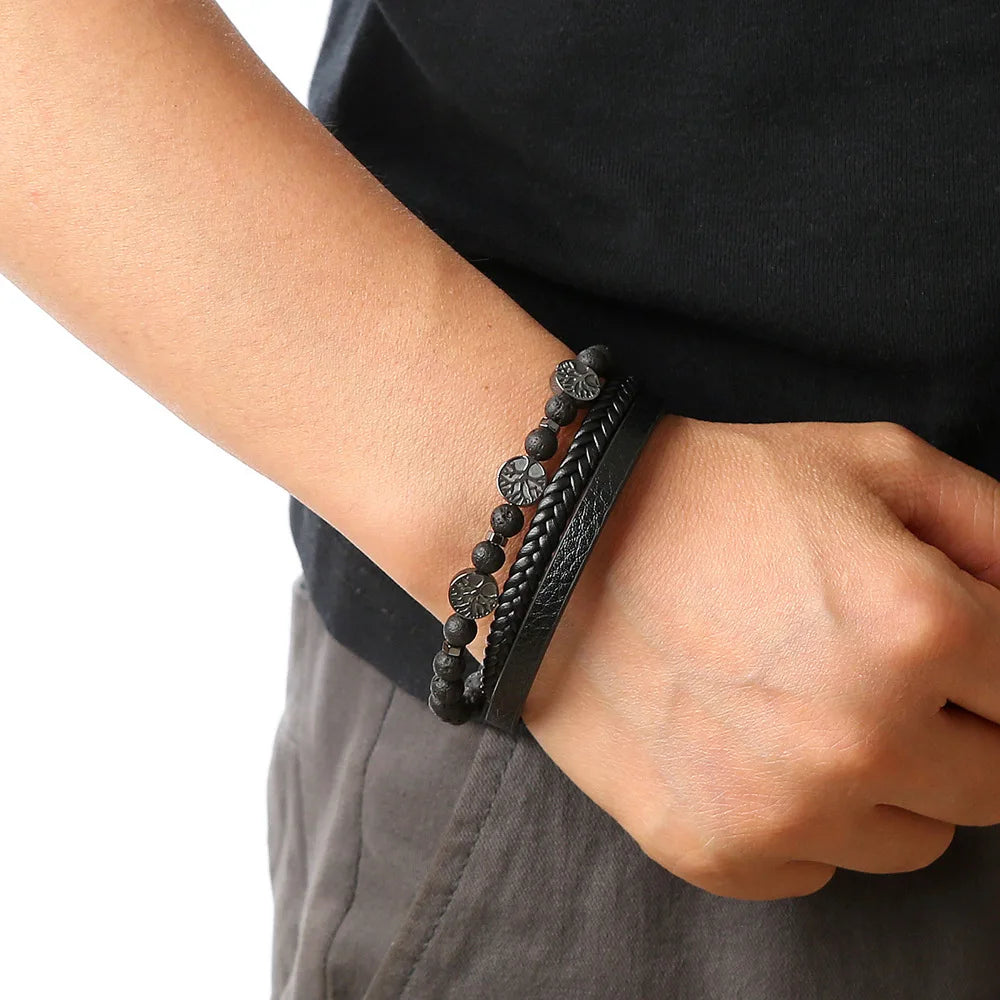 A close-up of a man's wrist wearing a black leather bracelet with tiger eye beads.