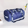A navy blue Nike backpack with white text is displayed on a white surface next to a small vase of yellow flowers.