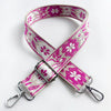A pink and white floral jacquard strap for a crossbody bag, featuring a silver buckle.