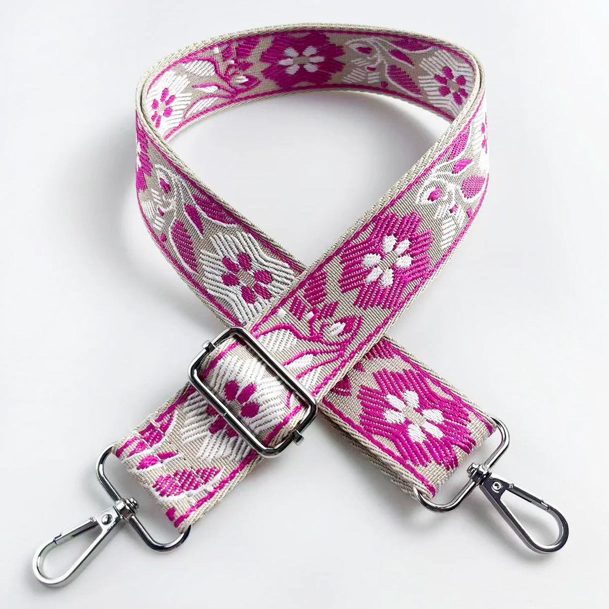 A pink and white floral jacquard strap for a crossbody bag, featuring a silver buckle.
