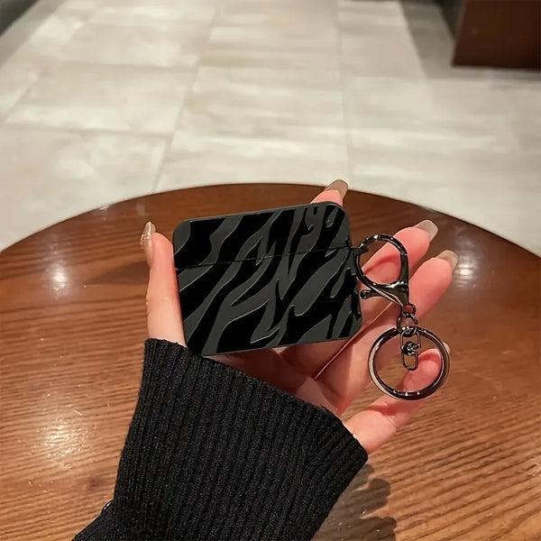 A black protective case with a zebra pattern is held in a hand against a wooden surface.