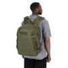 A man wearing a gray shirt is holding a tactical waterproof backpack.