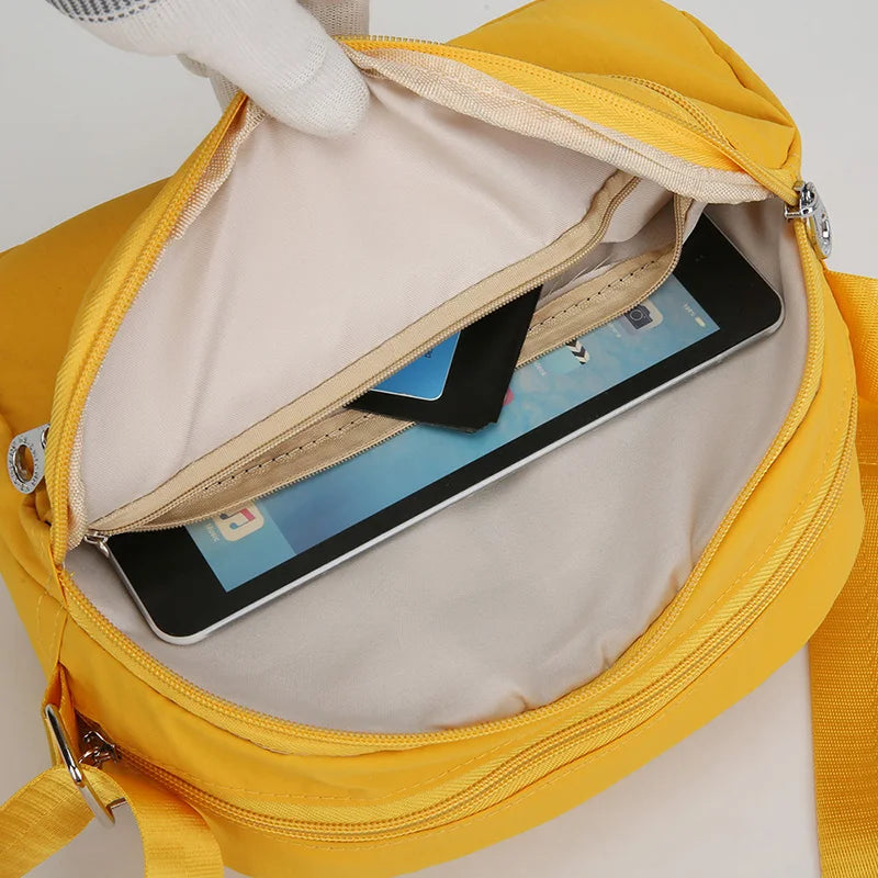 Gelbe Nylon-Crossbody-Tasche geöffnet, zeigt ein Smartphone darin.
