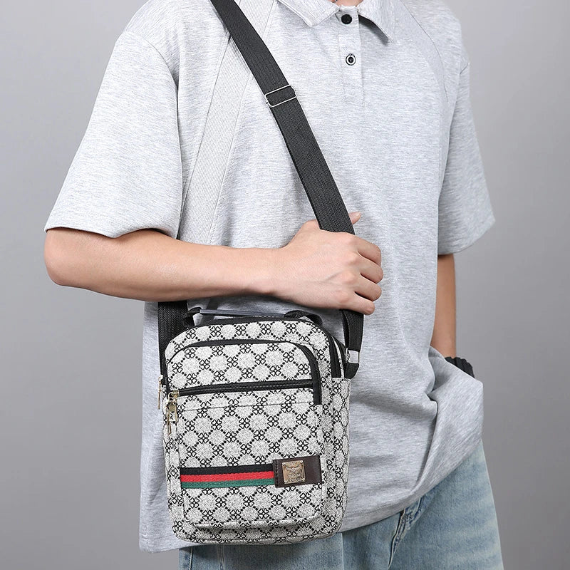A man wearing a gray shirt and jeans is holding a black and white patterned crossbody sling bag.