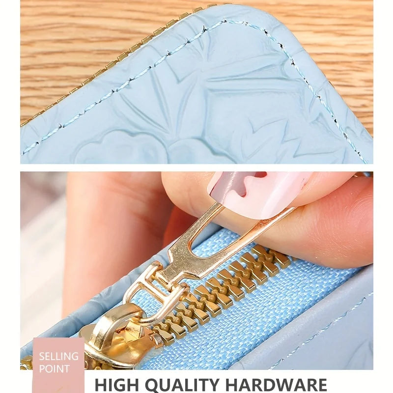Primer plano de una billetera de tarjeta de cuero sintético azul claro con estampado floral, herrajes dorados y un detalle de